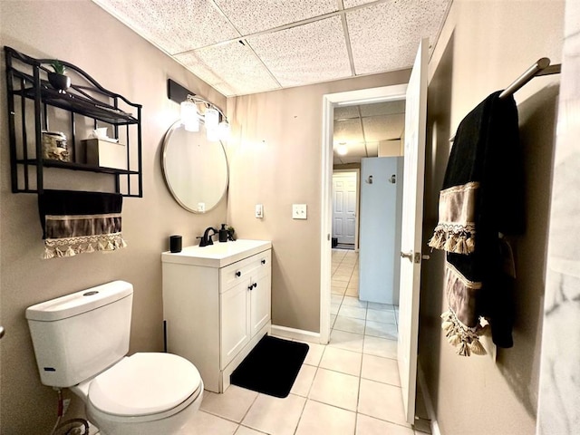 bathroom featuring vanity, tile patterned floors, toilet, and a drop ceiling