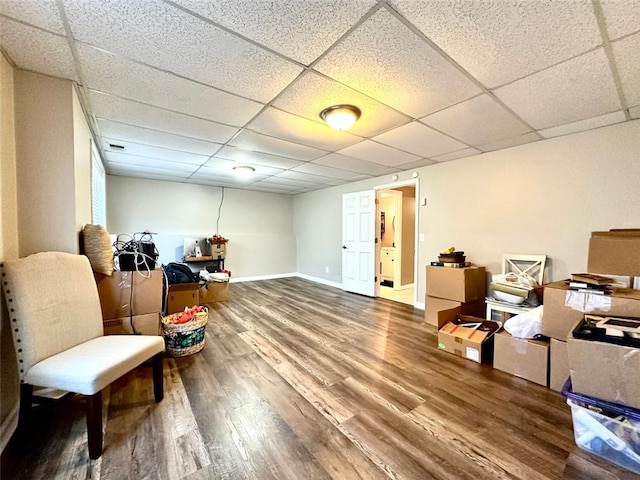 sitting room with a drop ceiling and wood-type flooring