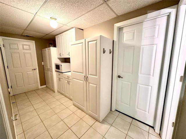 kitchen with white cabinetry, a paneled ceiling, and light tile patterned floors