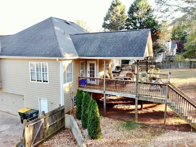 rear view of house featuring a garage and a wooden deck