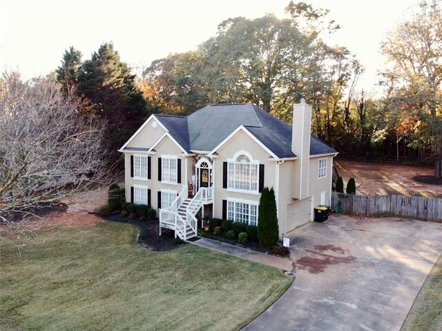 raised ranch with a garage, cooling unit, and a front yard