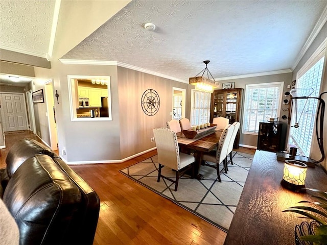 dining space with wood-type flooring, a textured ceiling, and crown molding