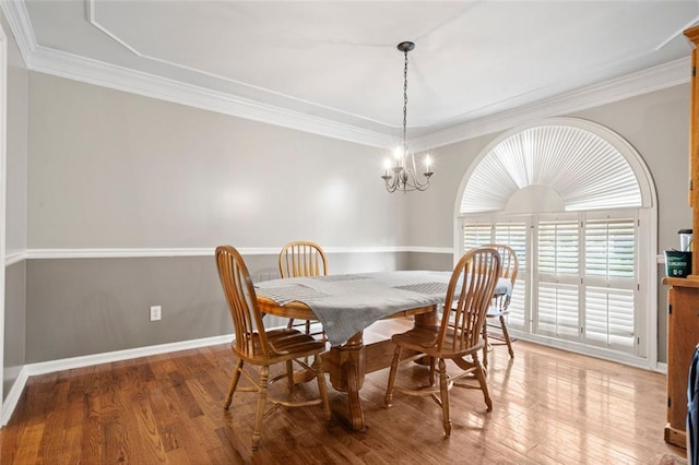 dining area with hardwood / wood-style floors, a notable chandelier, and crown molding