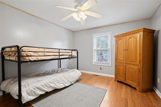 bedroom featuring ceiling fan, a textured ceiling, and light wood-type flooring