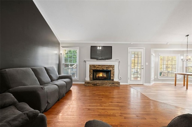 living room with a fireplace, a notable chandelier, ornamental molding, and light hardwood / wood-style flooring