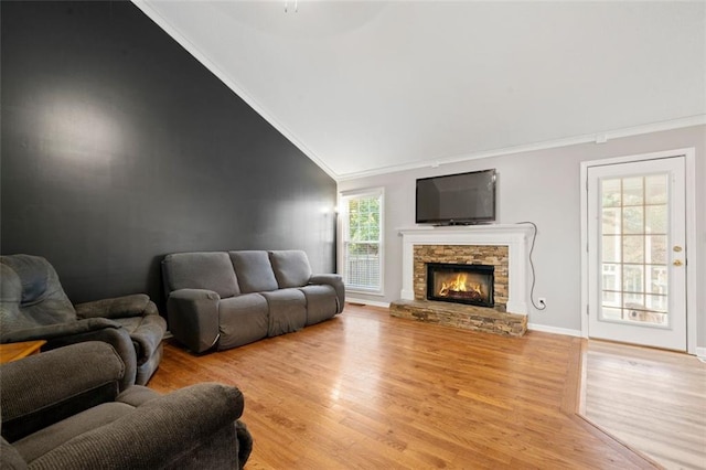 living room with a fireplace, lofted ceiling, crown molding, and light hardwood / wood-style flooring