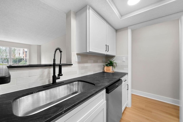 kitchen with decorative backsplash, stainless steel dishwasher, light wood-style floors, white cabinetry, and a sink