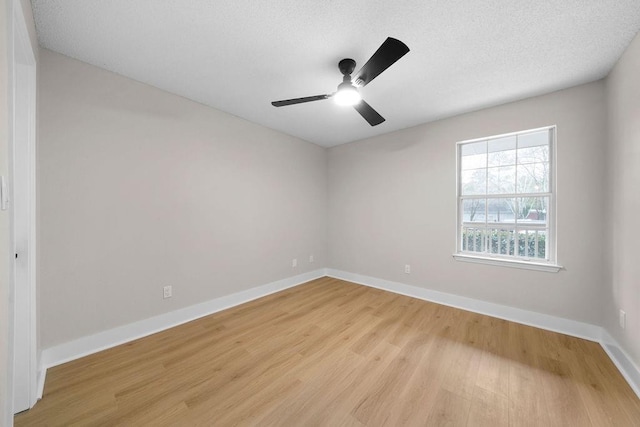 empty room featuring light wood-style floors, ceiling fan, baseboards, and a textured ceiling