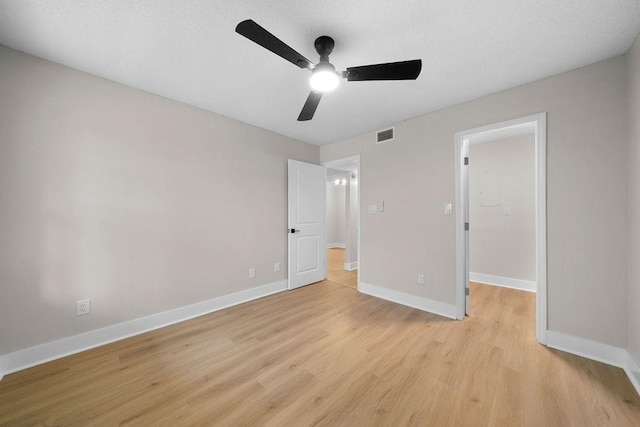 unfurnished bedroom featuring baseboards, a ceiling fan, visible vents, and light wood-style floors