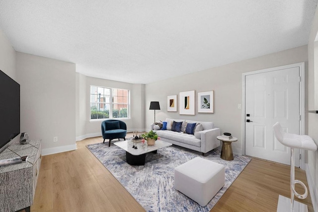 living area featuring baseboards, a textured ceiling, and light wood-style floors