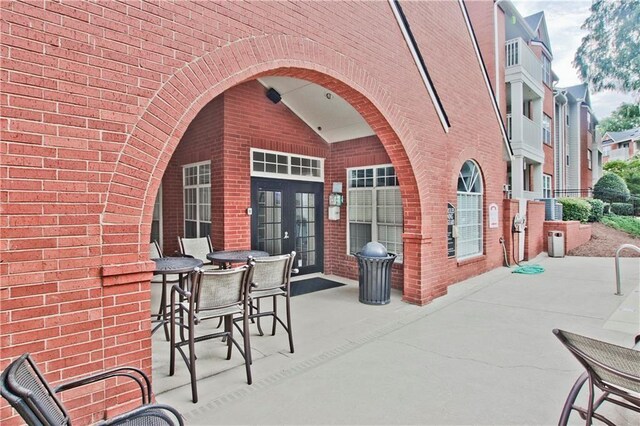 property entrance with brick siding, french doors, and a patio