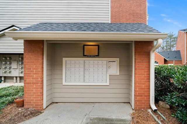 doorway to property with brick siding and roof with shingles