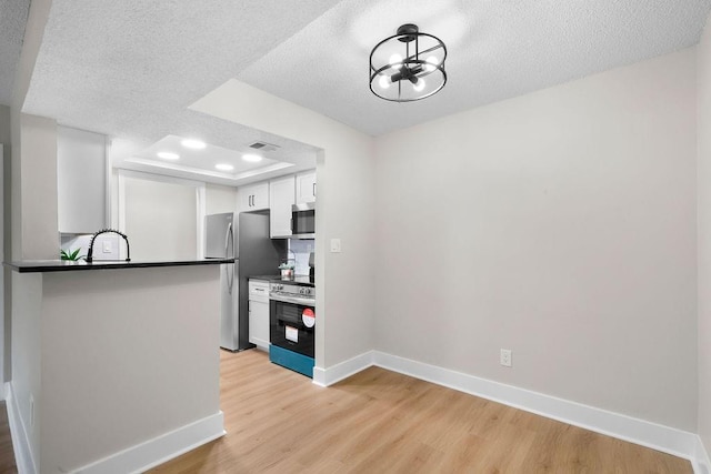 kitchen with appliances with stainless steel finishes, dark countertops, and light wood-style flooring