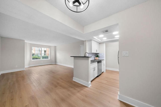 kitchen with light wood-style flooring, visible vents, baseboards, white cabinetry, and stainless steel dishwasher