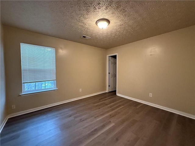 unfurnished room with visible vents, a textured ceiling, baseboards, and dark wood-style flooring