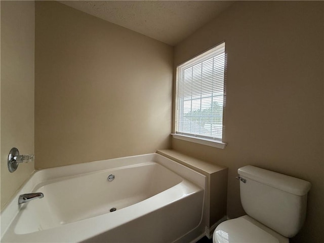 bathroom featuring a bath, a textured ceiling, and toilet