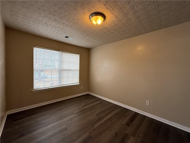 unfurnished room featuring dark wood-style floors, visible vents, a textured ceiling, and baseboards