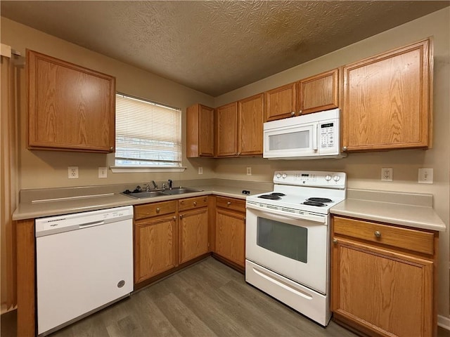 kitchen with a sink, white appliances, wood finished floors, and light countertops