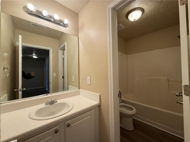 full bathroom with visible vents, a textured ceiling, vanity, and toilet