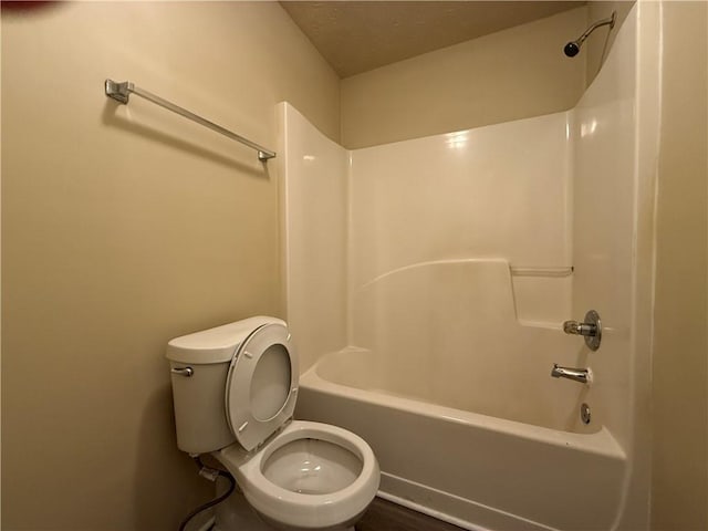 bathroom featuring toilet,  shower combination, and a textured ceiling