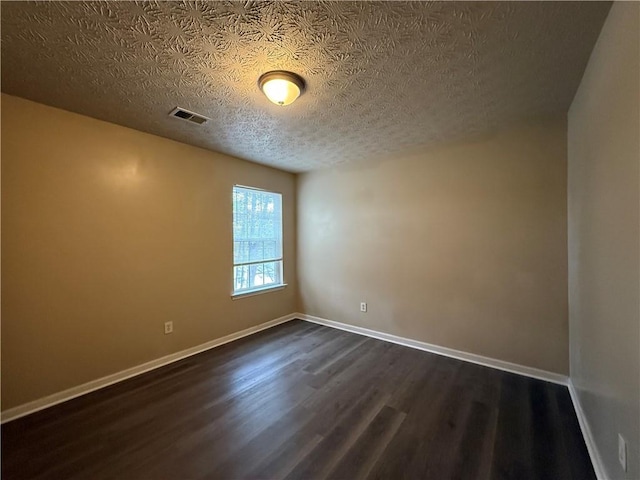 unfurnished room featuring dark wood-style floors, visible vents, a textured ceiling, and baseboards