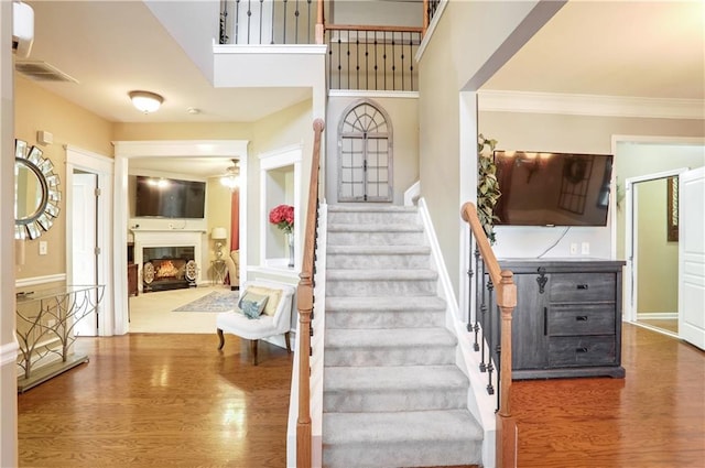 staircase with hardwood / wood-style flooring and ornamental molding