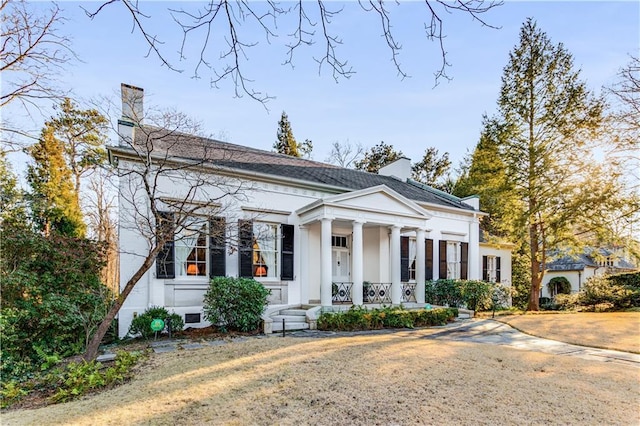 greek revival house with a porch and a chimney