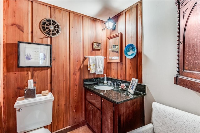 bathroom with wooden walls, toilet, and vanity