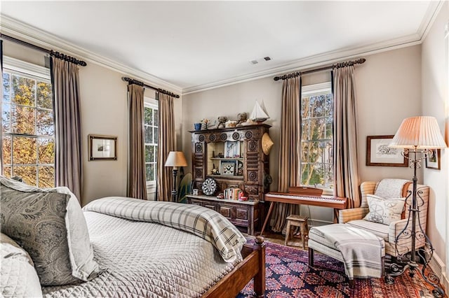 bedroom featuring baseboards, wood finished floors, visible vents, and ornamental molding