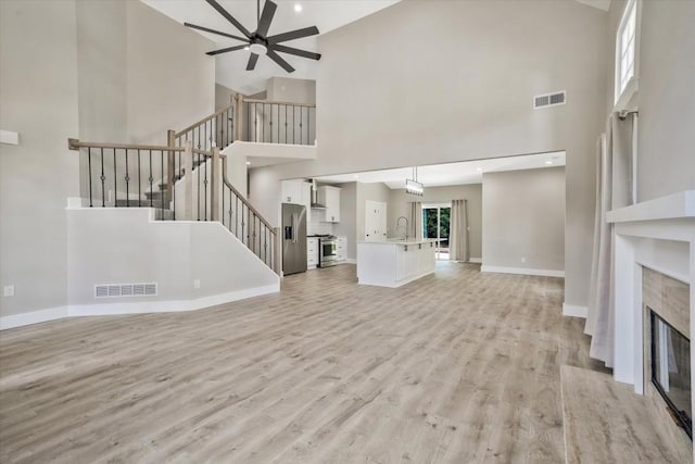 1950 Stethem Fry, Alpharetta, GA 30022 - unfurnished living room with high vaulted ceiling, ceiling fan, a fireplace, light wood-style flooring, and stairway