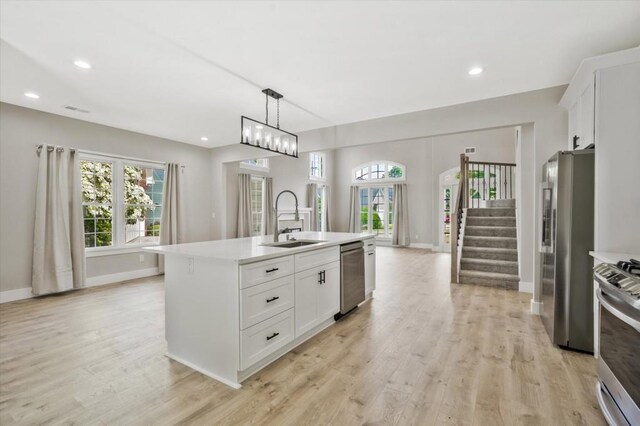 1950 Stethem Fry, Alpharetta, GA 30022 - kitchen featuring stainless steel appliances, light wood finished floors, light countertops, white cabinets, and a kitchen island with sink