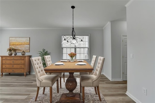 dining room featuring baseboards, a notable chandelier, light wood-style flooring, and crown molding