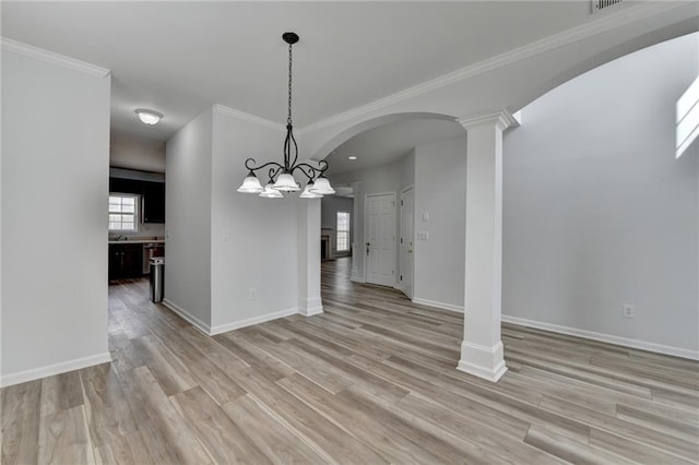 unfurnished dining area featuring arched walkways, baseboards, light wood-style flooring, and ornate columns