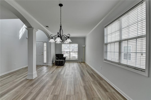 interior space featuring ornamental molding, arched walkways, decorative columns, and light wood finished floors