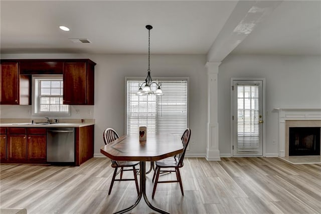 dining space featuring a fireplace, ornate columns, visible vents, light wood-style flooring, and baseboards