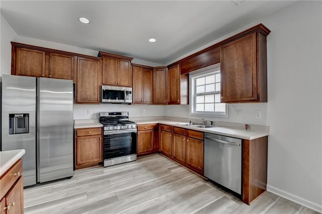 kitchen featuring light wood-style flooring, appliances with stainless steel finishes, light countertops, and a sink