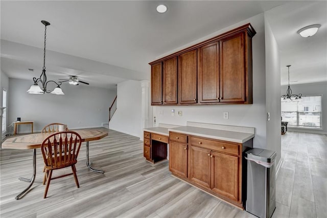 kitchen featuring hanging light fixtures, light wood finished floors, light countertops, and brown cabinetry