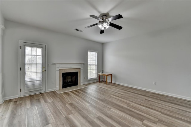 unfurnished living room featuring baseboards, a high end fireplace, visible vents, and light wood-style floors