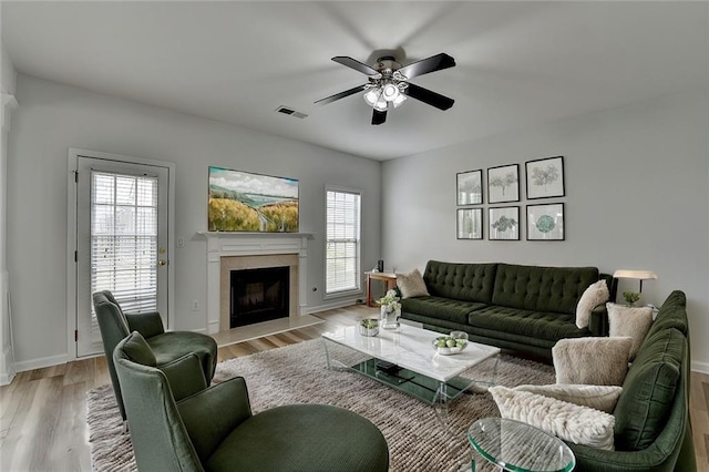 living area featuring visible vents, plenty of natural light, light wood-style flooring, and a fireplace