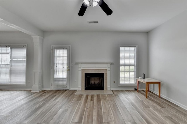 unfurnished living room with a healthy amount of sunlight, light wood-style flooring, visible vents, and a fireplace with flush hearth