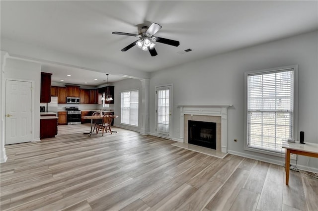 living room featuring light wood finished floors, baseboards, a fireplace, and visible vents