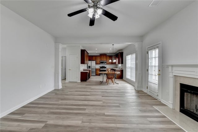 living room featuring light wood finished floors, recessed lighting, a premium fireplace, a ceiling fan, and baseboards