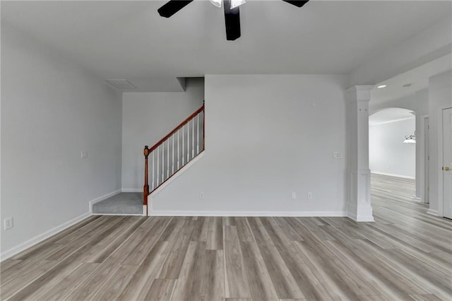 spare room featuring light wood-style floors, baseboards, stairs, and arched walkways