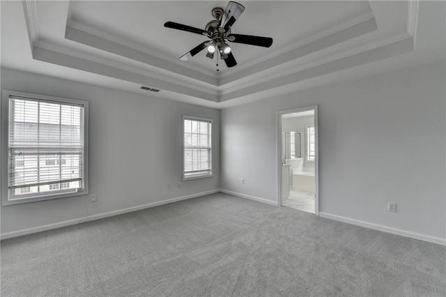 unfurnished room with carpet floors, visible vents, a raised ceiling, and crown molding