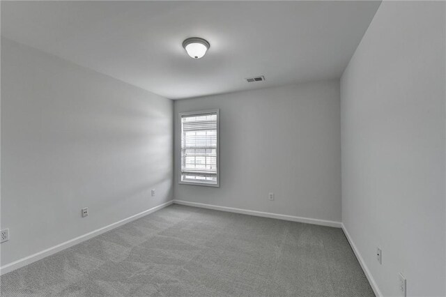 spare room with carpet floors, visible vents, and baseboards