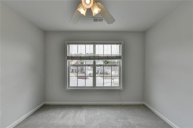 carpeted empty room with baseboards, visible vents, and ceiling fan