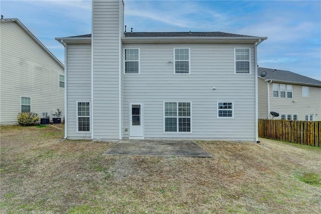 rear view of house with a patio, a chimney, central air condition unit, a lawn, and fence