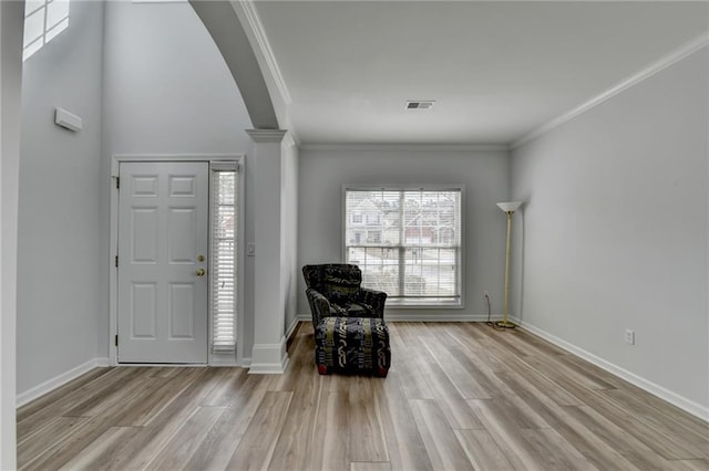 foyer with light wood finished floors, baseboards, visible vents, and crown molding