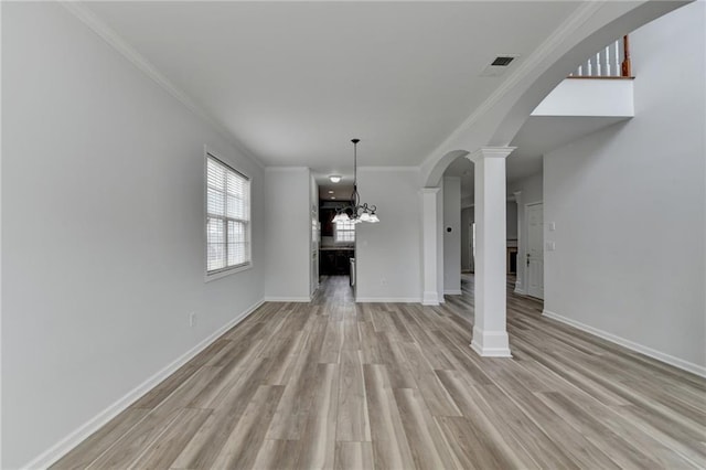 unfurnished living room with decorative columns, arched walkways, baseboards, crown molding, and light wood-type flooring