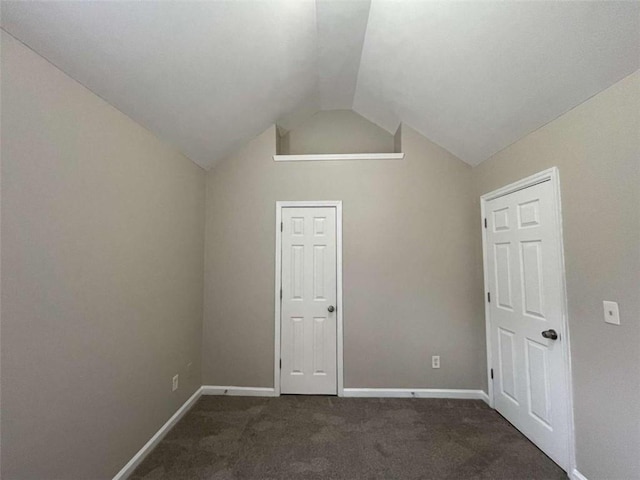 interior space featuring lofted ceiling and dark colored carpet